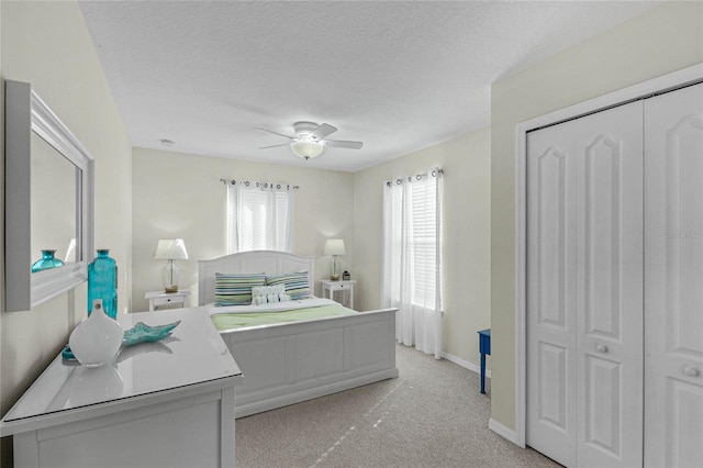 bedroom with ceiling fan, multiple windows, light carpet, and a closet