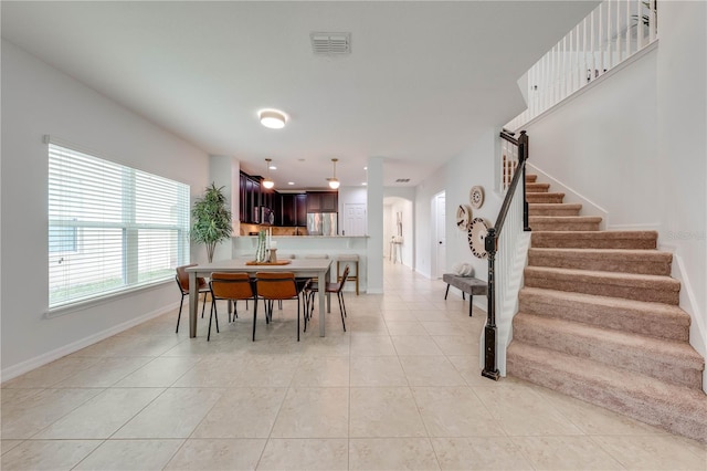 dining room with visible vents, baseboards, light tile patterned flooring, and stairway
