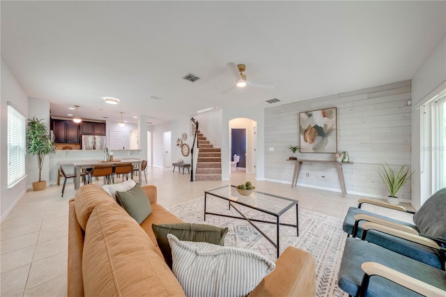 tiled living room with ceiling fan and wood walls