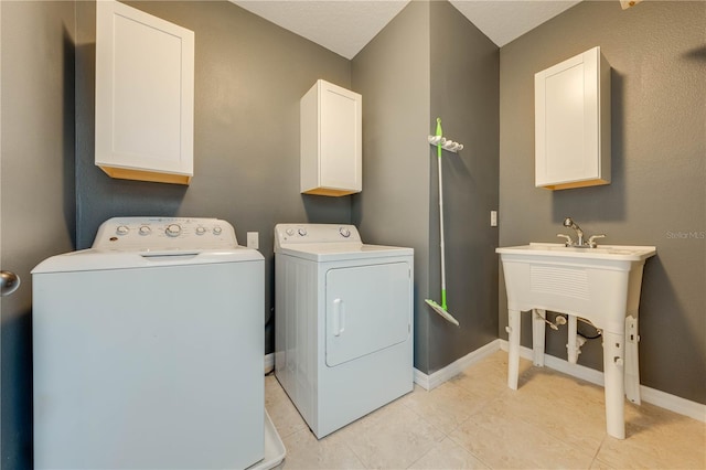 laundry area featuring washing machine and clothes dryer, light tile patterned floors, and cabinets