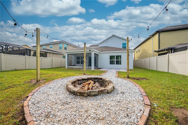 rear view of property featuring a yard, a fire pit, a patio area, and a sunroom