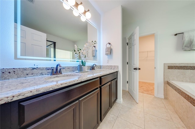 bathroom featuring tile patterned floors, vanity, and a relaxing tiled tub