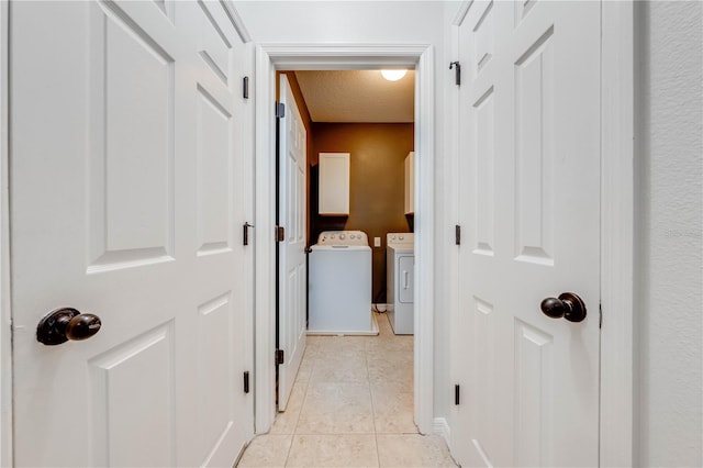 hallway featuring a textured ceiling, washing machine and dryer, and light tile patterned floors