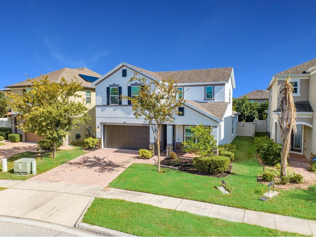 5249 Villa Rosa Ave, Saint Cloud, FL 34771 - view of front of home with decorative driveway, stucco siding, a garage, roof with shingles, and a gate