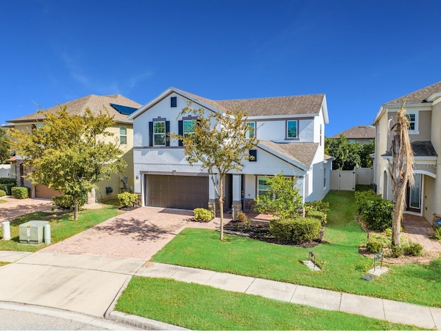 traditional home with stucco siding, an attached garage, decorative driveway, and a front lawn