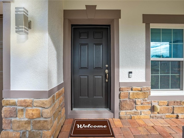 entrance to property featuring stucco siding and stone siding