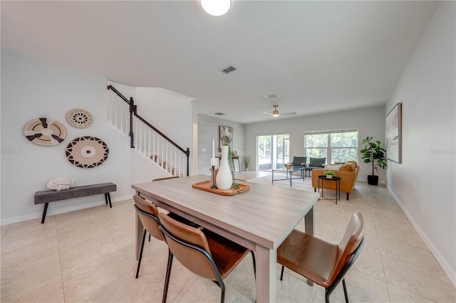 dining space with a ceiling fan, visible vents, light tile patterned floors, and stairway