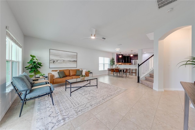 living room featuring stairway, arched walkways, light tile patterned floors, and visible vents