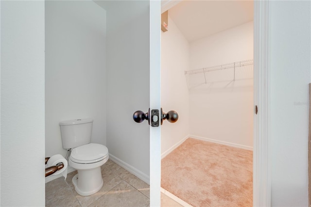 bathroom featuring toilet, baseboards, and a walk in closet