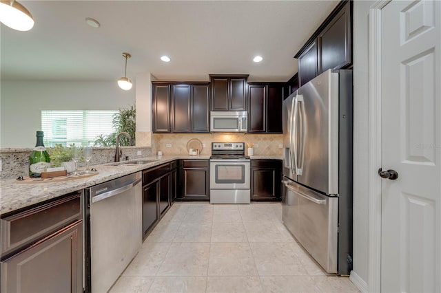 kitchen with decorative backsplash, dark brown cabinetry, light stone countertops, a sink, and appliances with stainless steel finishes