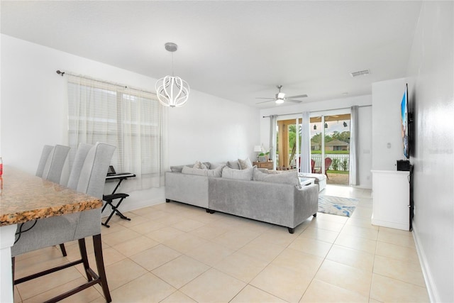 living room featuring ceiling fan with notable chandelier and light tile patterned floors