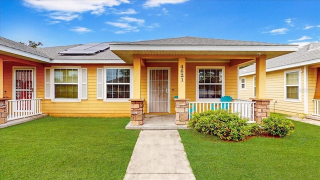 entrance to property featuring a yard, solar panels, and a porch