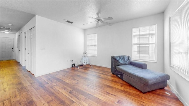 sitting room featuring a textured ceiling, hardwood / wood-style flooring, a healthy amount of sunlight, and ceiling fan