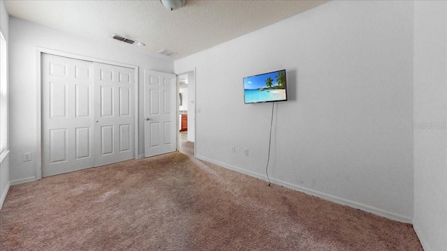 unfurnished bedroom featuring a closet, a textured ceiling, and carpet floors