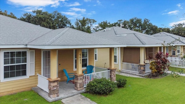 back of house featuring covered porch and a yard