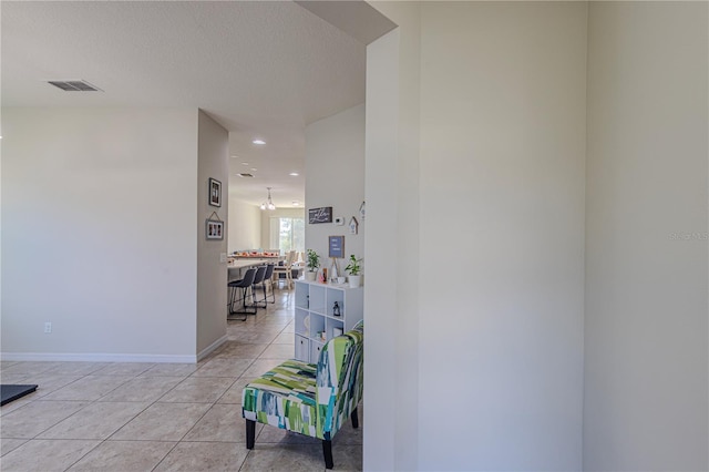 hall featuring light tile patterned floors and a textured ceiling