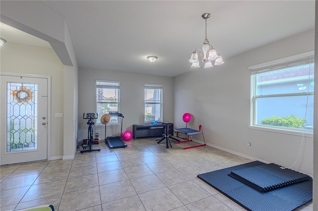 workout room with a notable chandelier and light tile patterned floors