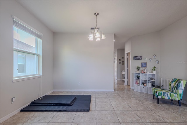 exercise area with a notable chandelier and light tile patterned flooring