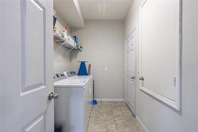 laundry area with separate washer and dryer and light tile patterned floors