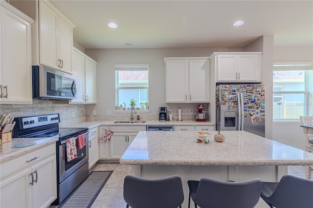 kitchen with a breakfast bar, appliances with stainless steel finishes, a kitchen island, and sink