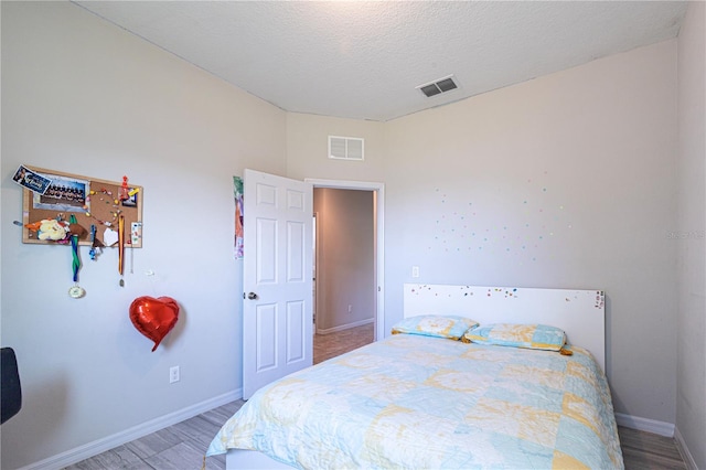 bedroom with hardwood / wood-style floors and a textured ceiling