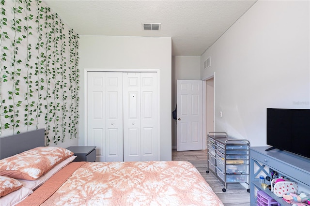 bedroom featuring wood-type flooring, a textured ceiling, and a closet