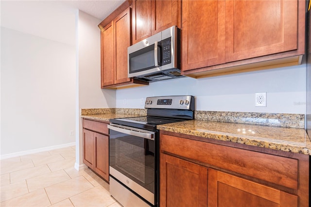 kitchen with light tile patterned floors, light stone countertops, and appliances with stainless steel finishes