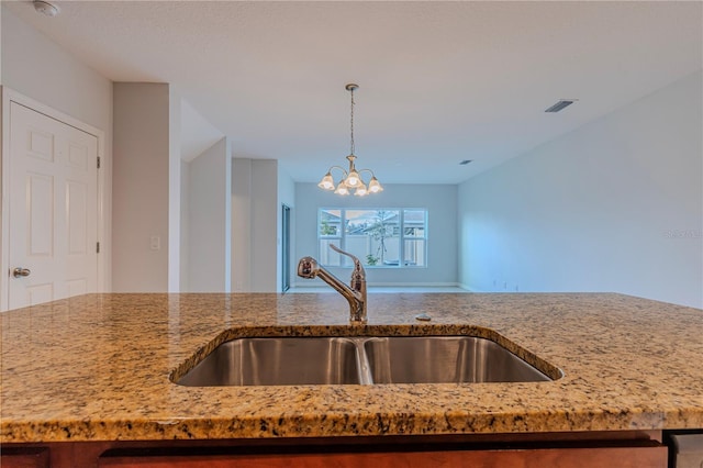 kitchen featuring hanging light fixtures, sink, a chandelier, and light stone counters