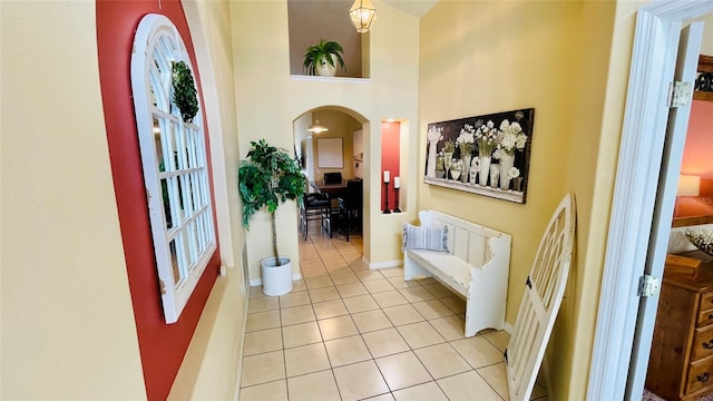 entryway with light tile patterned flooring and a towering ceiling