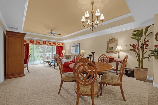 dining area featuring a tray ceiling, light carpet, crown molding, and ceiling fan with notable chandelier