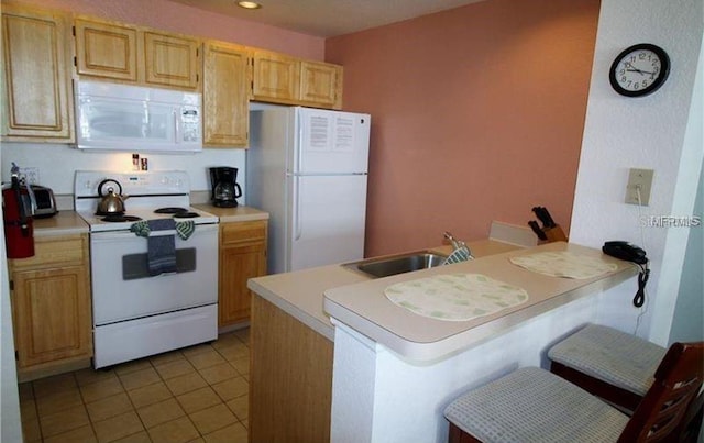 kitchen featuring white appliances, light brown cabinets, sink, a breakfast bar area, and kitchen peninsula