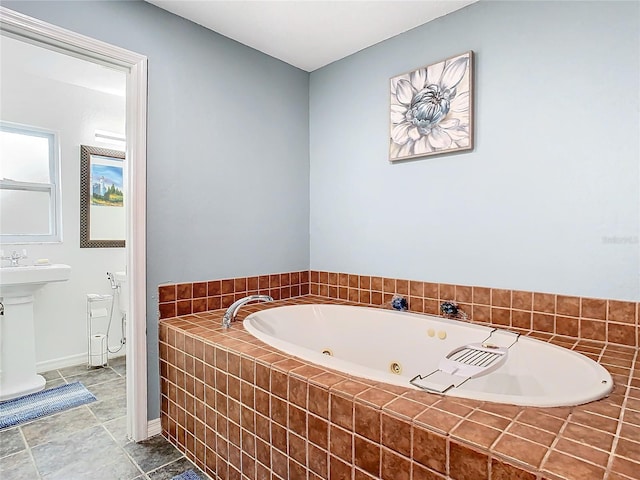 bathroom with sink, toilet, and tiled bath