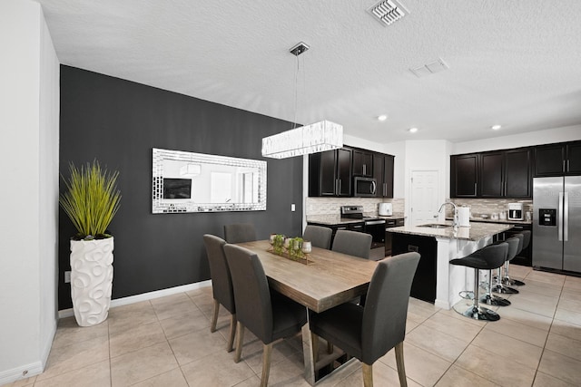 dining area featuring a textured ceiling, light tile patterned floors, and sink