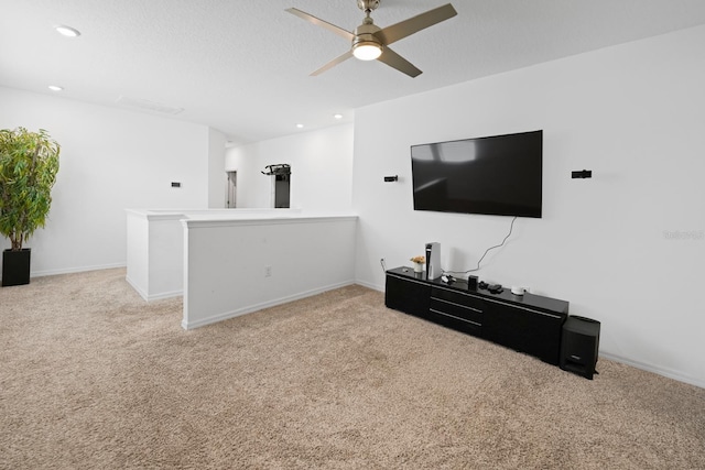 living room with ceiling fan, light colored carpet, and a textured ceiling