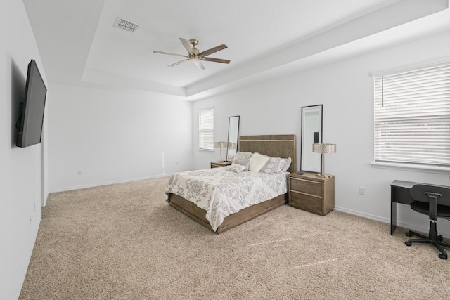 carpeted bedroom featuring ceiling fan and a raised ceiling