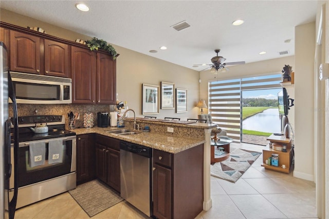 kitchen featuring kitchen peninsula, appliances with stainless steel finishes, a water view, and sink