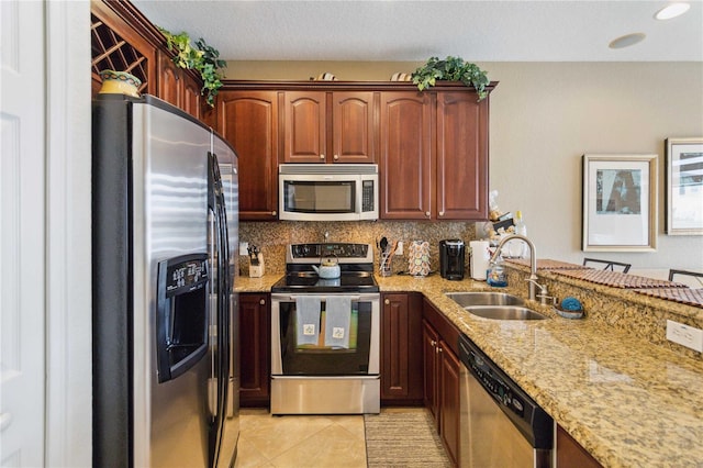 kitchen with tasteful backsplash, light stone counters, light tile patterned flooring, stainless steel appliances, and sink