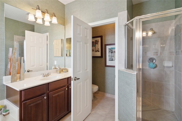 bathroom featuring a shower with shower door, vanity, toilet, and tile patterned flooring