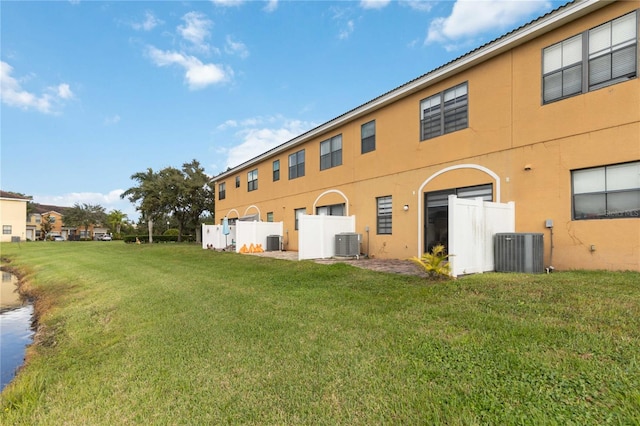 back of property featuring central air condition unit and a yard