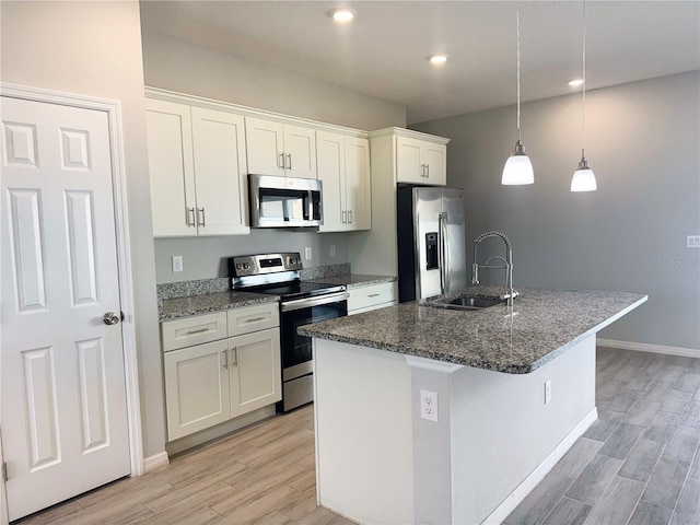 kitchen with stainless steel appliances, sink, decorative light fixtures, an island with sink, and white cabinets