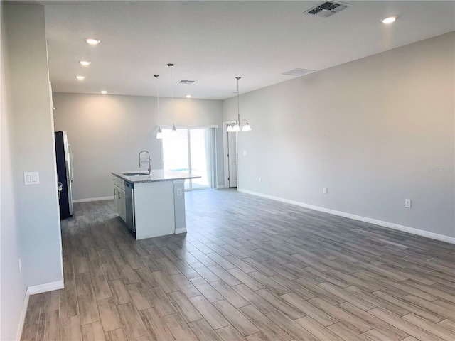 kitchen with stainless steel appliances, a center island with sink, decorative light fixtures, and hardwood / wood-style floors