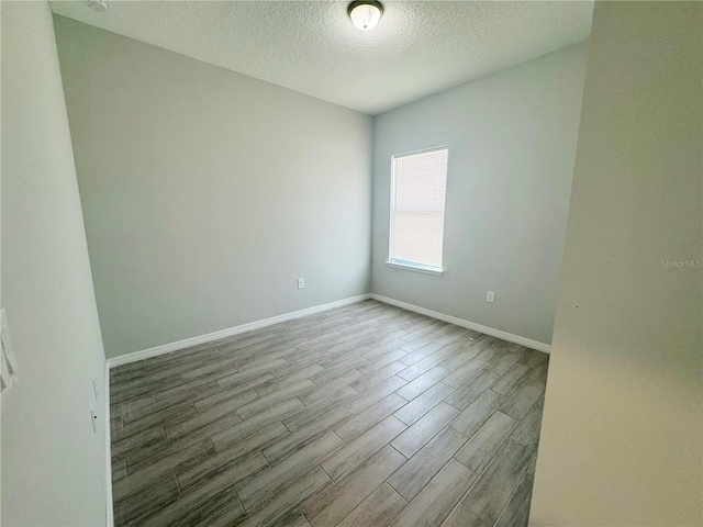 spare room featuring a textured ceiling and light hardwood / wood-style flooring