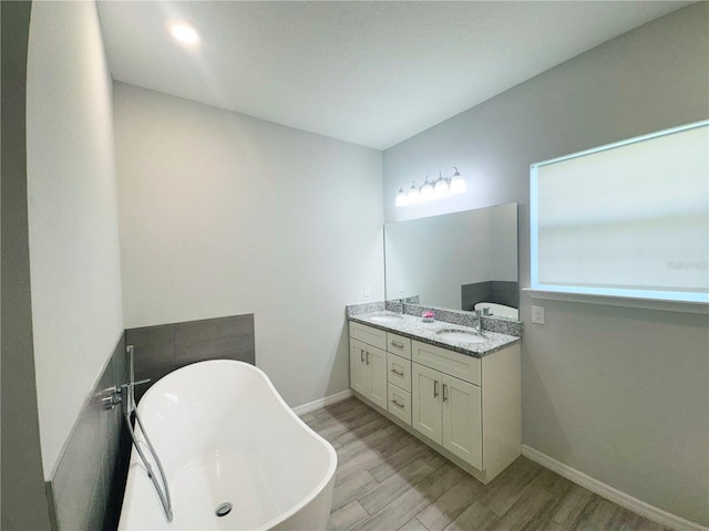 bathroom with a bathtub, vanity, and hardwood / wood-style flooring