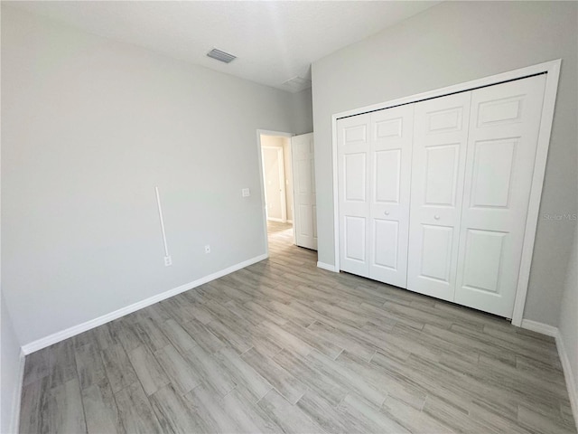 unfurnished bedroom with a closet and light wood-type flooring