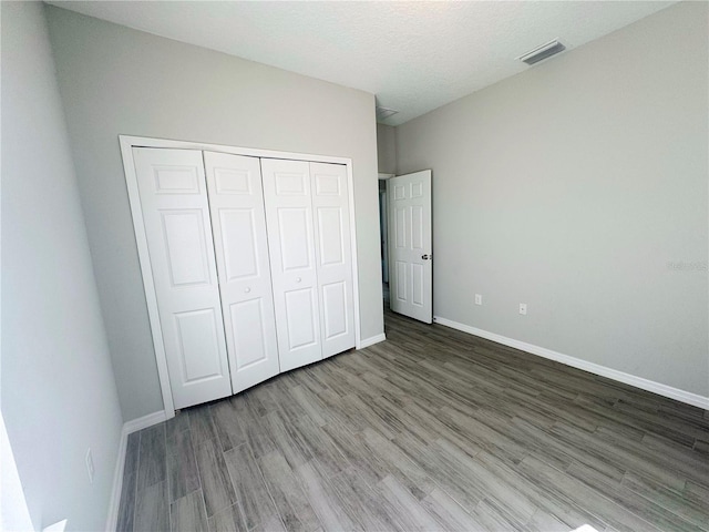 unfurnished bedroom featuring wood-type flooring, a textured ceiling, and a closet