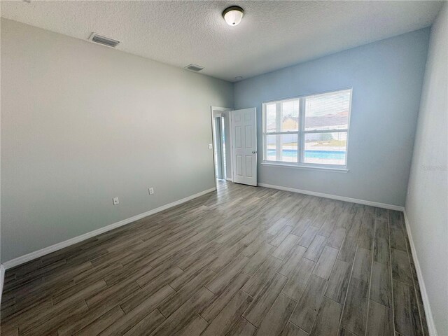 spare room with a textured ceiling and dark hardwood / wood-style floors