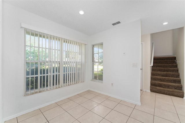 tiled empty room with a textured ceiling