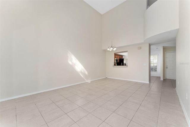 unfurnished living room with a chandelier, a towering ceiling, and light tile patterned floors