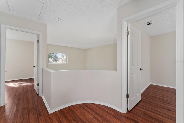 hall featuring a textured ceiling and dark wood-type flooring