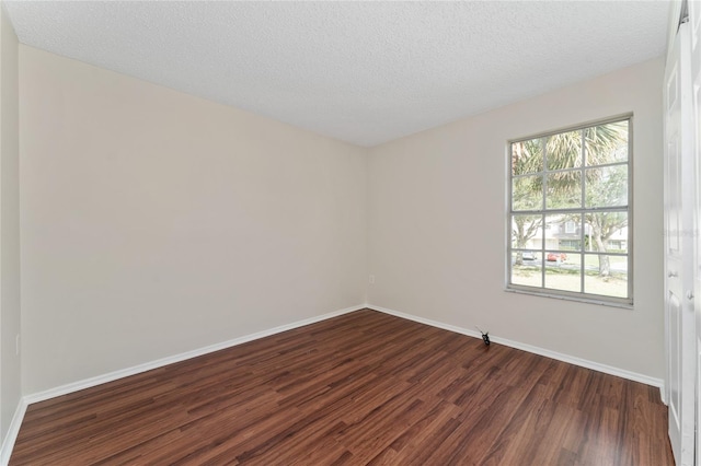 unfurnished room with a textured ceiling and dark hardwood / wood-style flooring